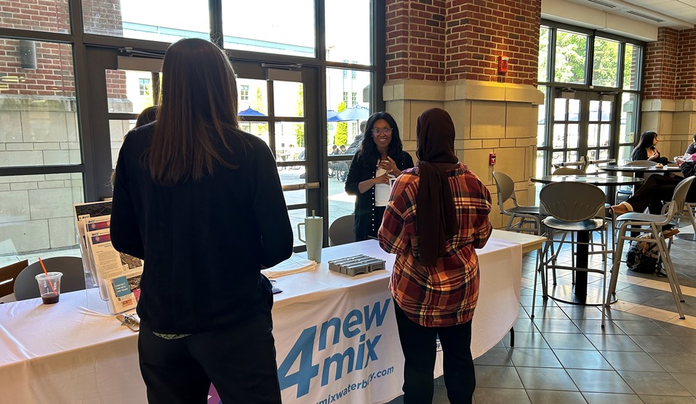 event staff talking with event attendees in front of the event table